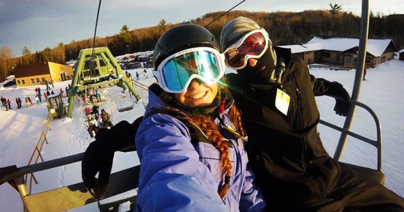 Two smiling people on a chair lift in Gaylord, MI at Treetops Resort.