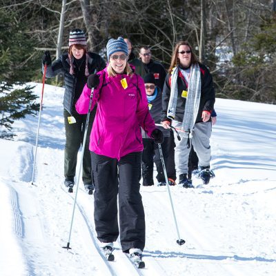 Group of women cross country skiing and snowshoeing on snowy trails at Treetops Resort in Gaylord Michigan