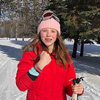 Teenage girl in red jacket on skis
