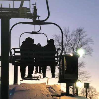 skiers on a chairlift at sunset