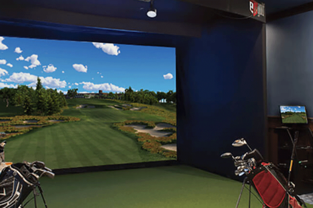 The indoor golf simulator screen at Treetops Resort with bags of golf clubs