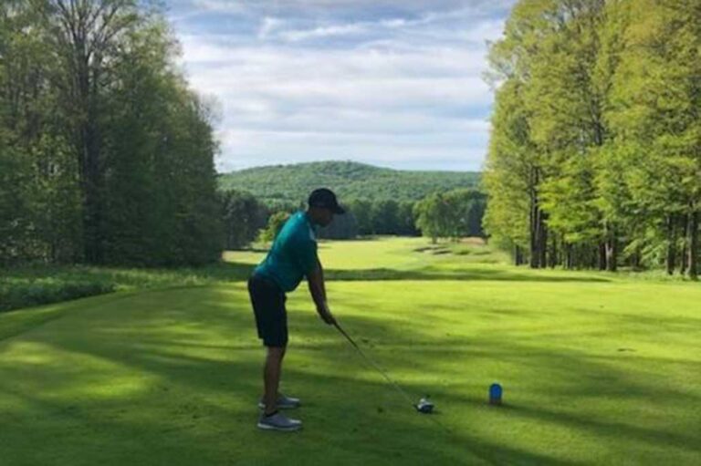 Man in golf attire holding a drive ready to hit a golf ball | proper golf stance