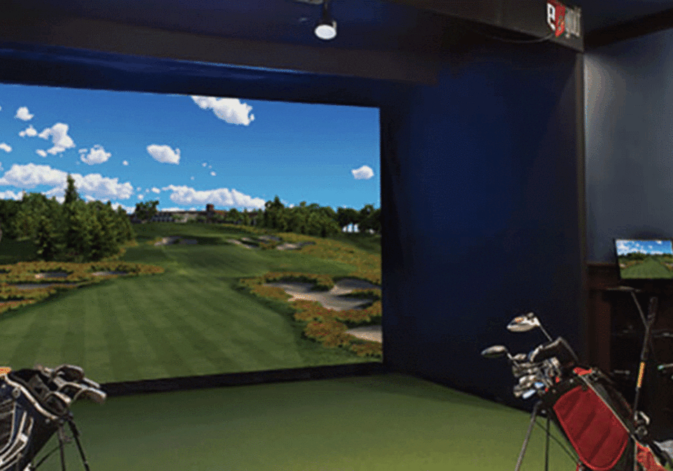 The indoor golf simulator screen at Treetops Resort with bags of golf clubs