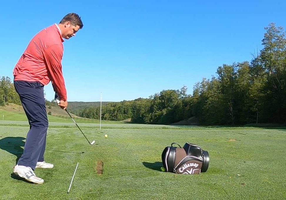 Tall man in read shirt getting ready to swing a golf club | golf practice station